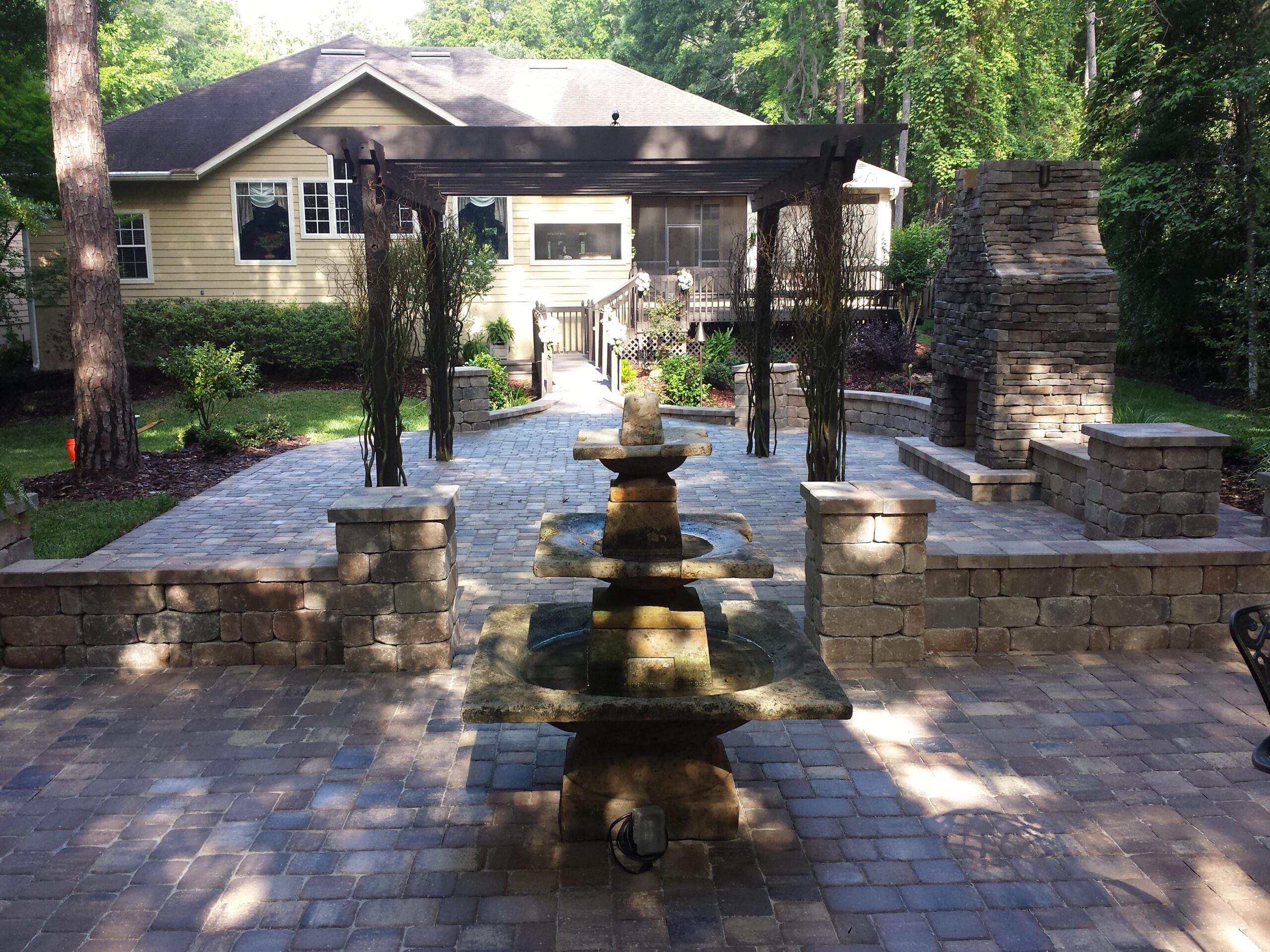 Concrete paver patio, block seating wall, fire place with stone veneer, and pergola. Paver and block color-Sierra. Custom pergola is painted pressure treated southern yellow pine.