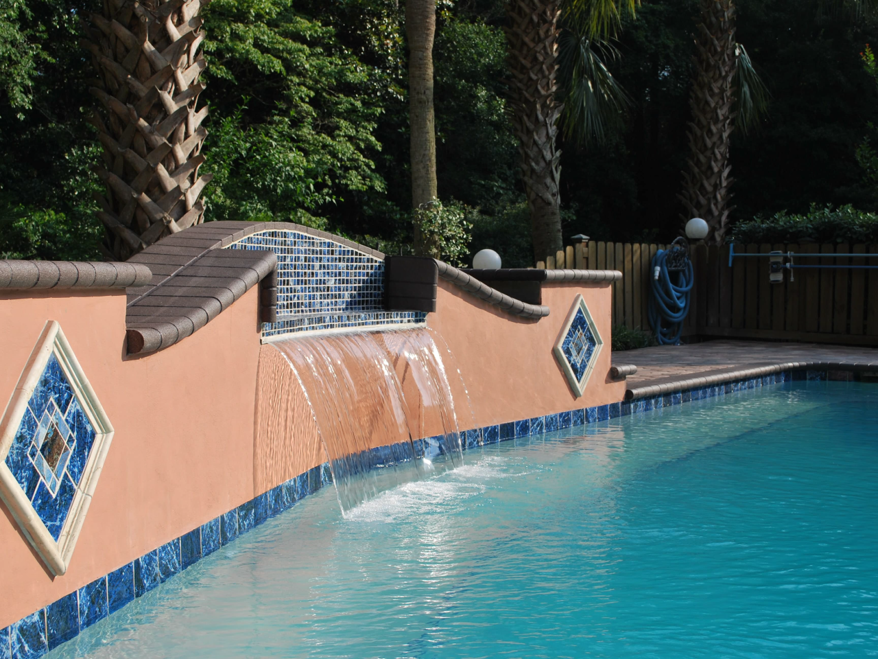 Water feature with stucco finish, concrete coping, glass tile spillway, and Ivory travertine tile accents.
