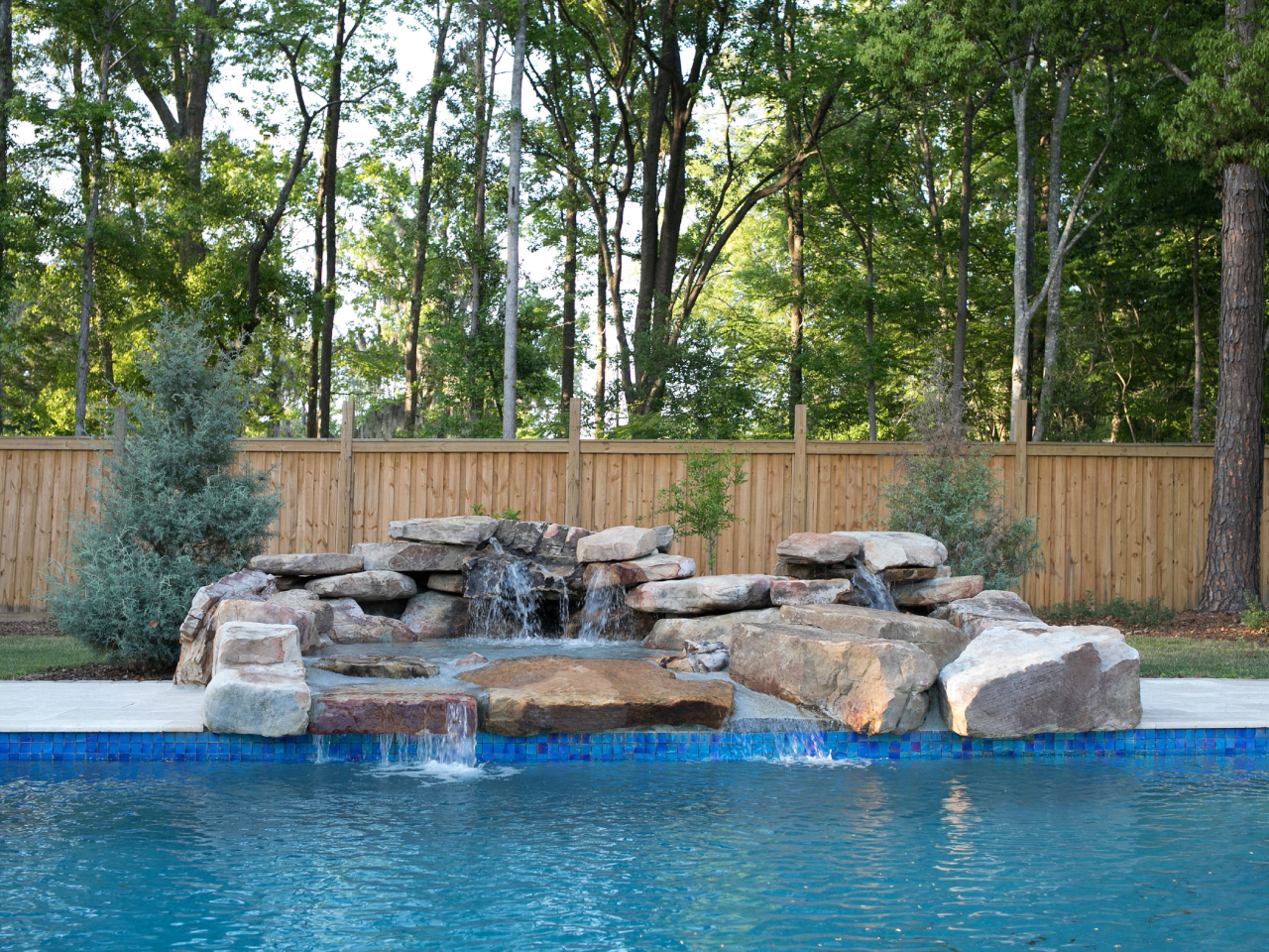 Travertine paver pool deck remodel with natural Stone boulder waterfall. Paver shape-French Pattern, color-Ivory.